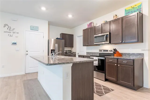 a kitchen with stainless steel appliances granite countertop a sink stove and refrigerator