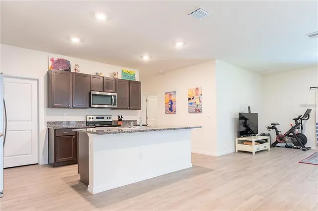 a kitchen with stainless steel appliances a stove top oven a sink dishwasher and a refrigerator with wooden floor