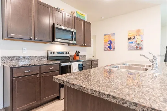 a kitchen with stainless steel appliances granite countertop a sink and a microwave