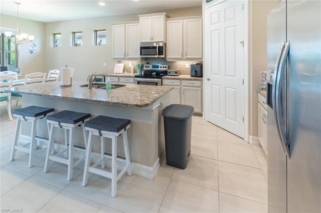 16366 Barclay Court Naples, FL 34110 - Photo 6 of 35 a kitchen with stainless steel appliances granite countertop a table chairs microwave and sink