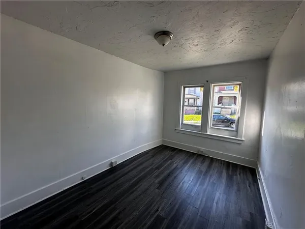 a view of an empty room with window and wooden floor