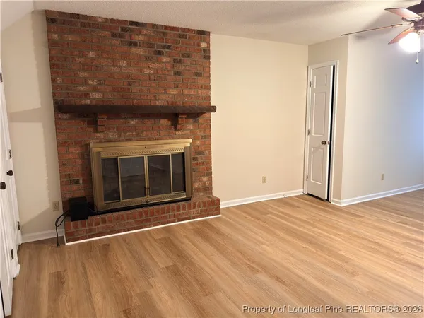 an empty room with wooden floor and fireplace