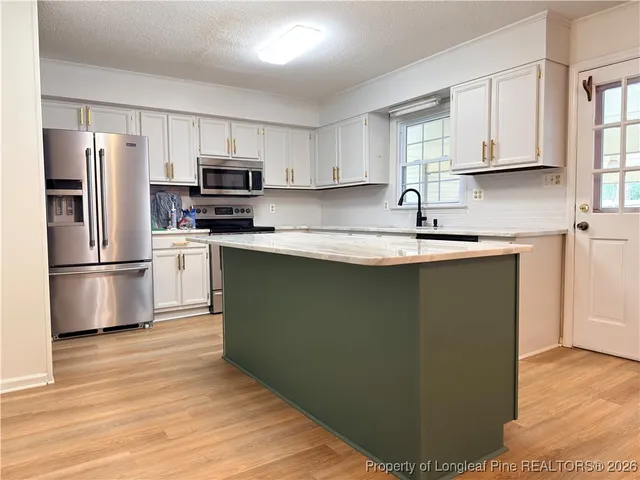 a kitchen with stainless steel appliances granite countertop a refrigerator sink and microwave