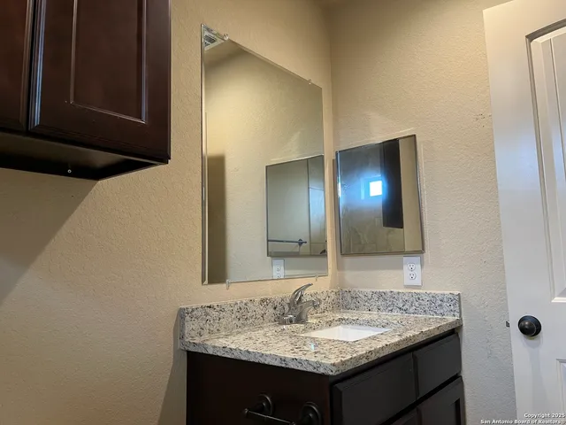 a bathroom with a granite countertop sink and a mirror