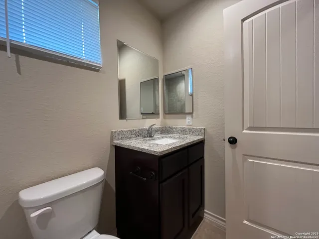 a bathroom with a granite countertop toilet and sink