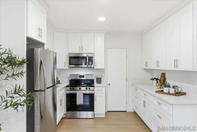a kitchen with stainless steel appliances a refrigerator a stove and white cabinets
