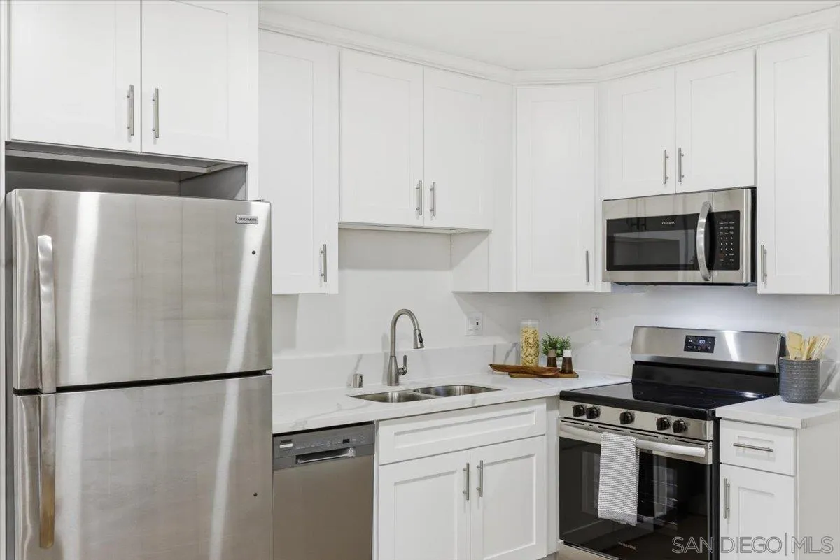911 Jamacha Road El Cajon, CA 92019 - Photo 12 of 34 a white kitchen with stainless steel appliances a refrigerator a stove a sink and white cabinets