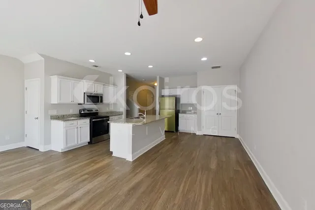 a kitchen with stainless steel appliances kitchen island wooden floors stove and white cabinets