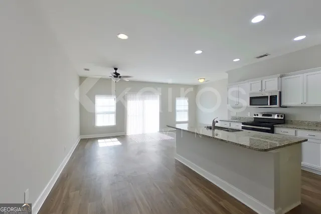 a kitchen with stainless steel appliances a sink a stove a refrigerator and cabinets