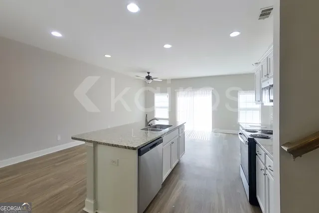 a kitchen with kitchen island a sink appliances wooden floor and a window