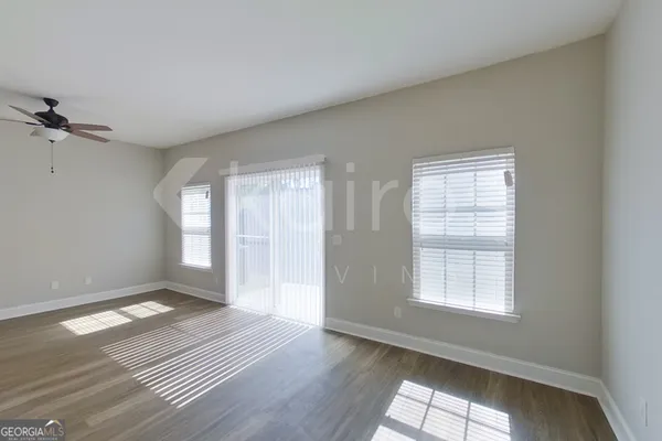 an empty room with wooden floor and windows