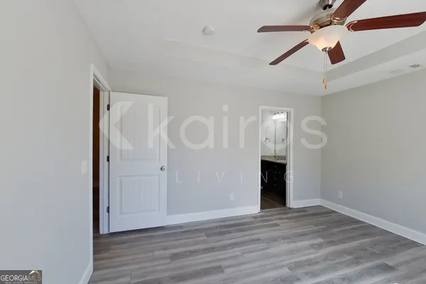 an empty room with wooden floor ceiling fan and windows