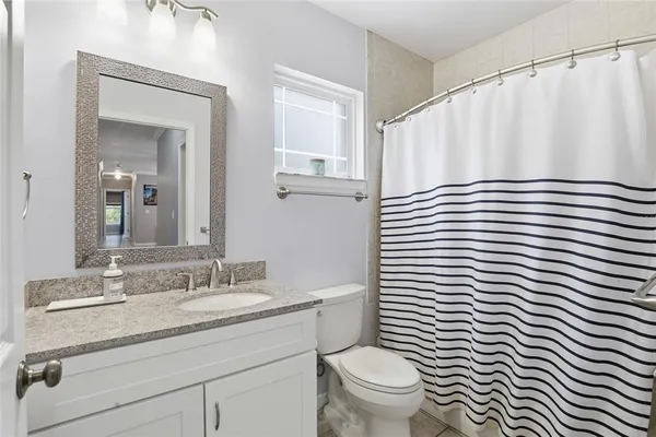 a bathroom with a sink a toilet a mirror and shower curtain