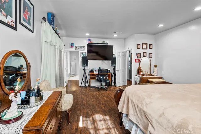 a bedroom with bed a flat tv screen and a bookshelf