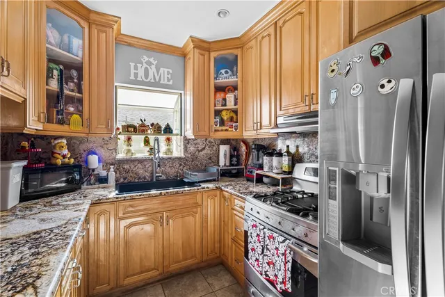 a kitchen with stainless steel appliances granite countertop a refrigerator a stove and a sink