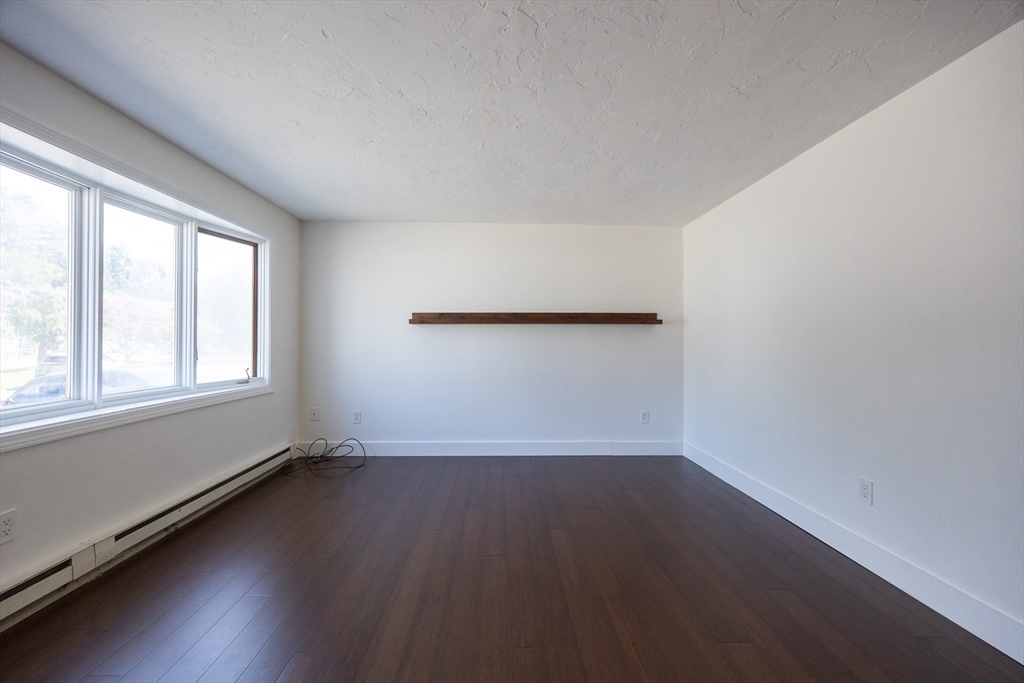 19 Cedar Square, Unit 19 Millis, MA 02054 - Photo 7 of 42 an empty room with wooden floor and windows