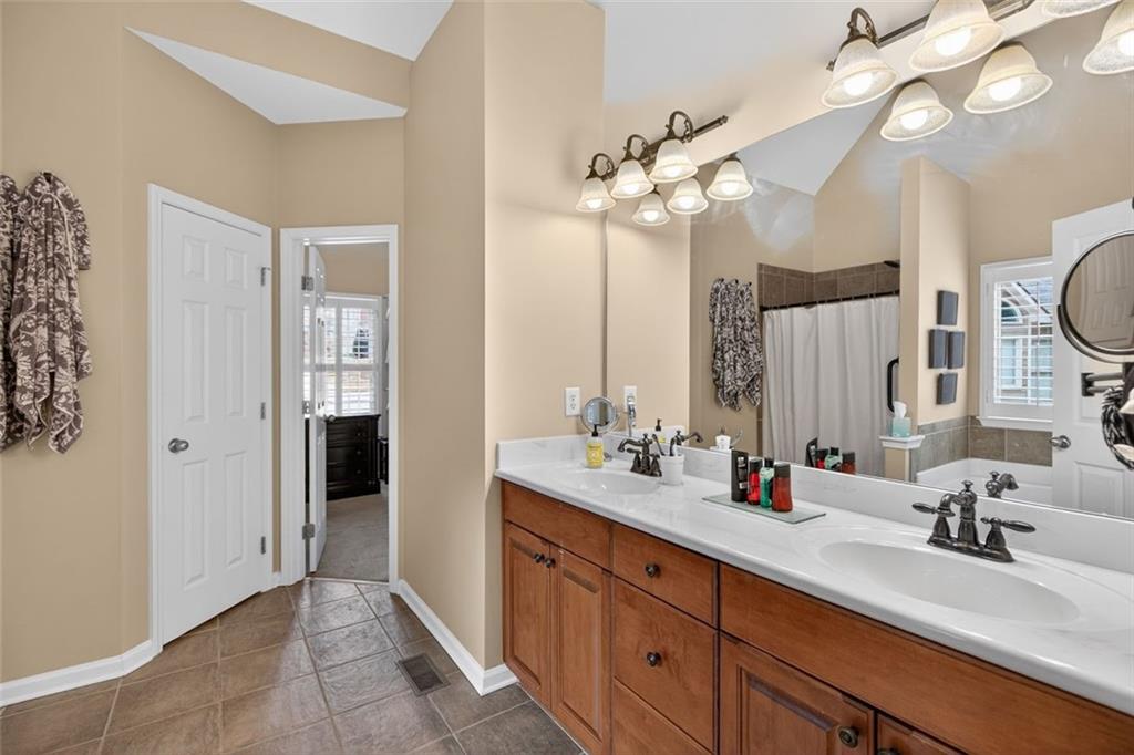 129 Dorchester Way Villa Rica, GA 30180 - Photo 25 of 65 a bathroom with a double vanity sink a mirror and a shower