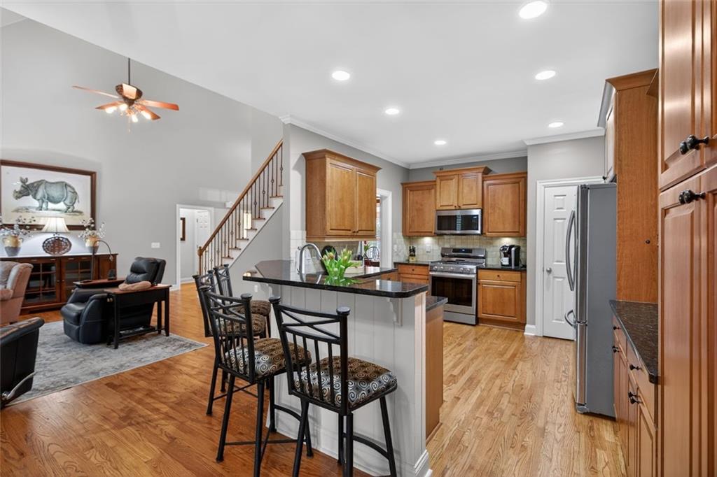 129 Dorchester Way Villa Rica, GA 30180 - Photo 10 of 65 a kitchen with stainless steel appliances kitchen island granite countertop a refrigerator a stove a sink a dining table and chairs with wooden floor
