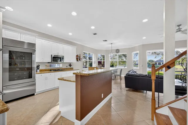 a kitchen with stainless steel appliances kitchen island granite countertop a refrigerator a stove and a sink with wooden floor