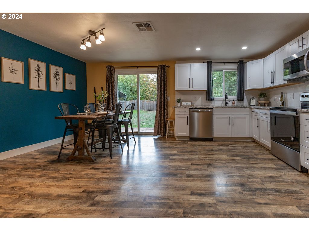2102 Delta Street Eugene, OR 97404 - Photo 35 of 35 a open kitchen with stainless steel appliances granite countertop a stove top oven a dining table and chairs with wooden floor