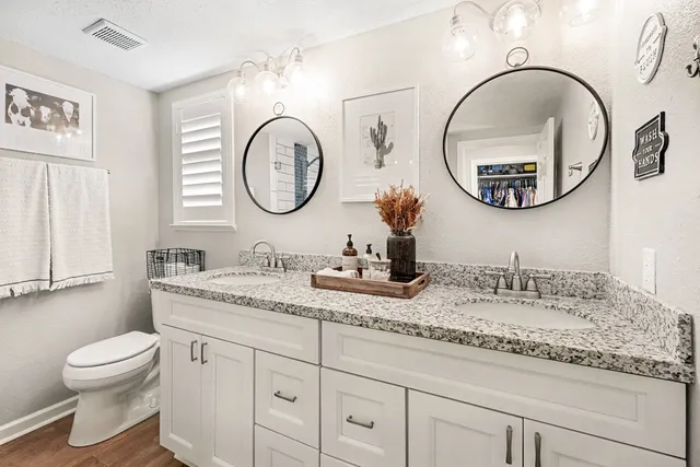 a bathroom with a granite countertop double vanity sink and a mirror
