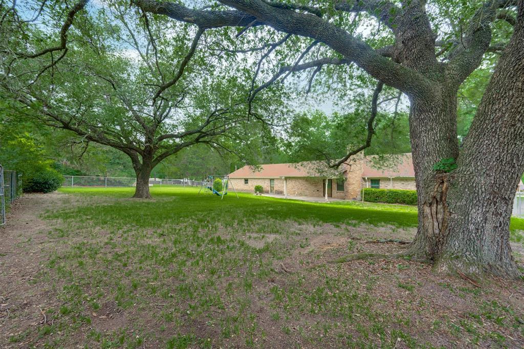 8798 Hill N Dale Road Tyler, TX 75709 - Photo 29 of 31 Expansive backyard featuring mature trees, a manicured lawn, and a perimeter chain-link fence
