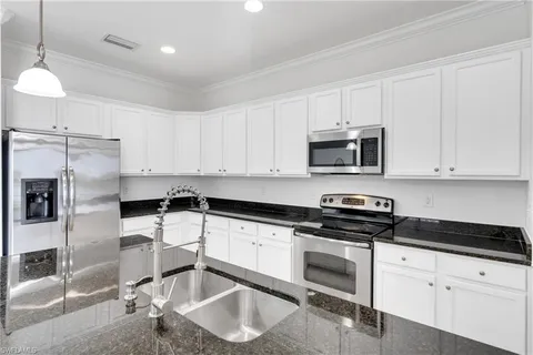 a outdoor kitchen with stainless steel appliances kitchen island granite countertop a dining table chairs sink and a granite counter top