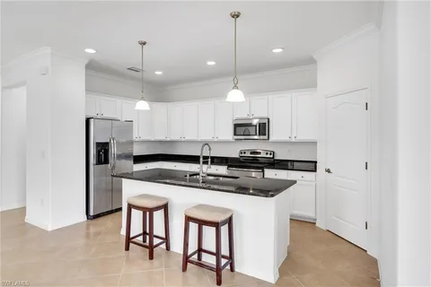 a kitchen with stainless steel appliances granite countertop a sink a stove a refrigerator and island
