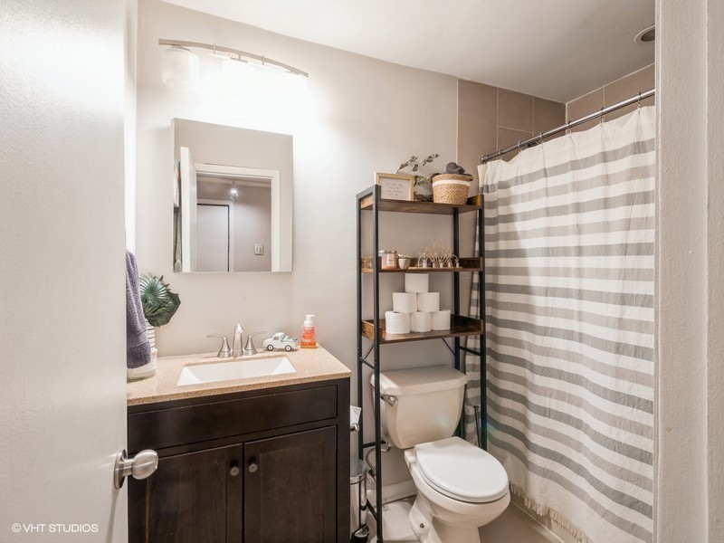 1038 West Byron Street, Unit 2E Chicago, IL 60613 - Photo 9 of 11 a bathroom with a sink a toilet a shower and a mirror