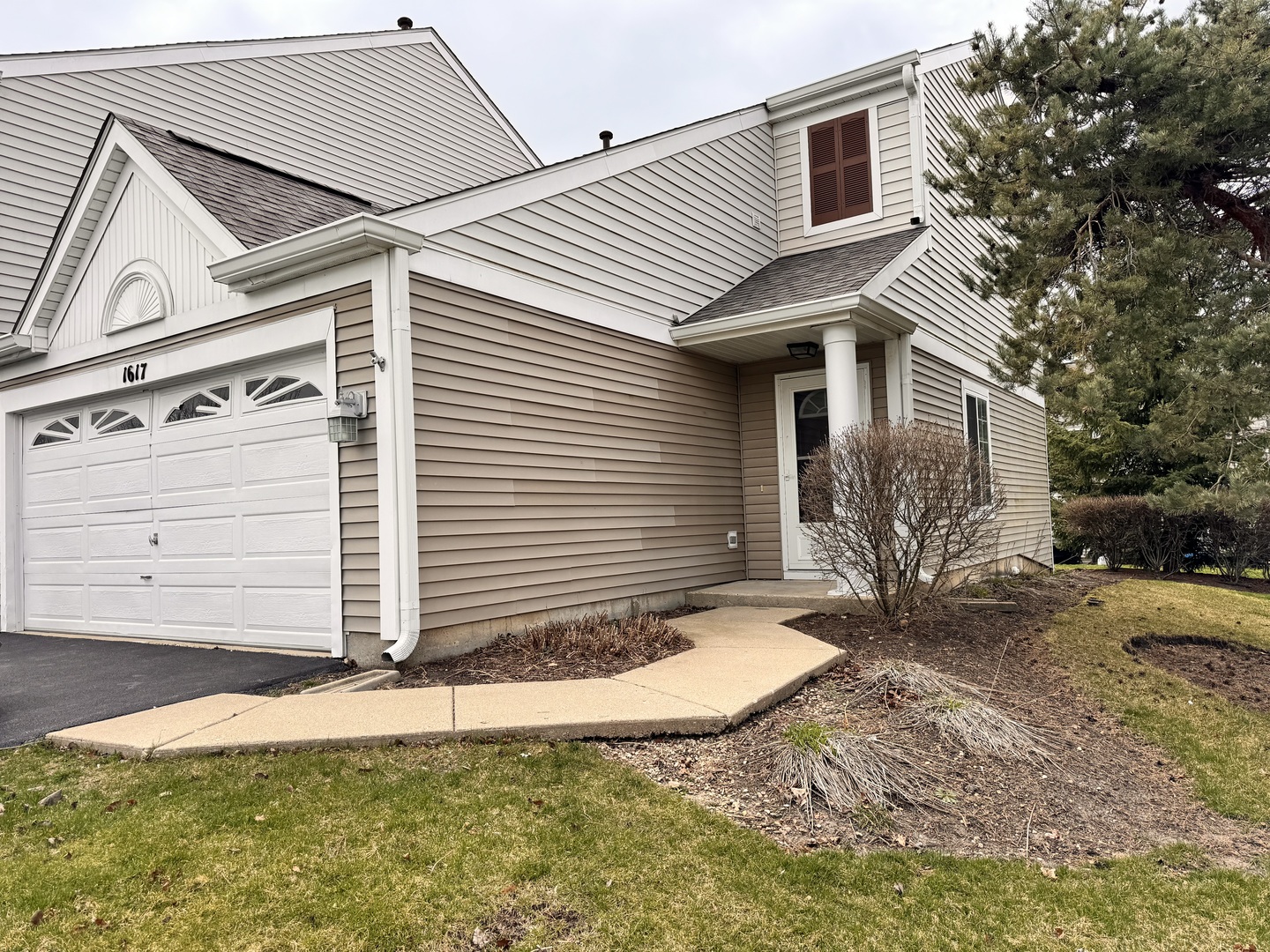 a view of a white house with a small yard and wooden fence