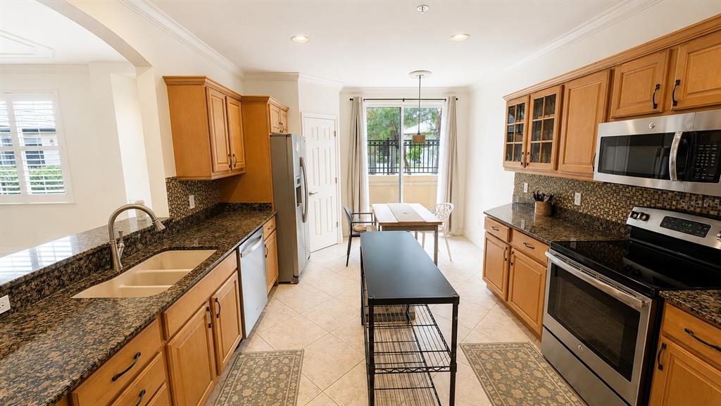 6552 Moorings Point Circle, Unit 102 Lakewood Ranch, FL 34202 - Photo 10 of 57 a kitchen with stainless steel appliances granite countertop a stove a sink and a microwave