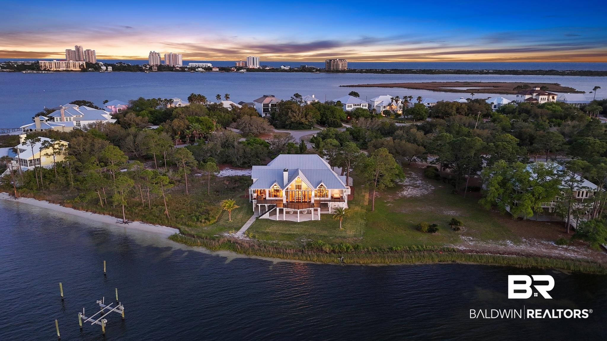33349 River Road Orange Beach, AL 36561 - Photo 2 of 61 Waterfront property featuring a prominent residence with a large elevated deck, a white sand shoreline, a private dock structure, and mature trees encompassing the lot