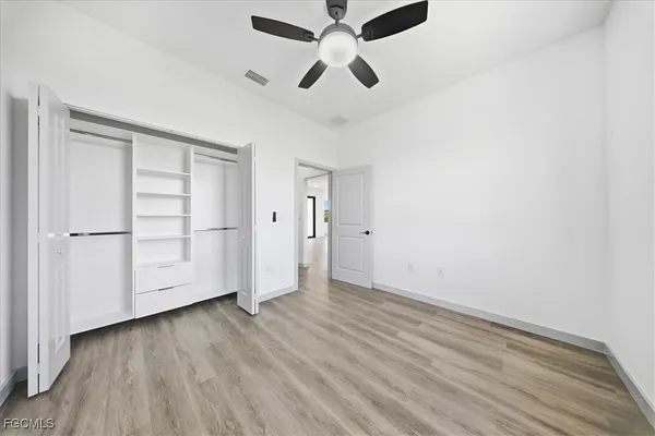 an empty room with wooden floor a ceiling fan and closet