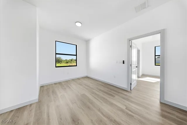 an empty room with wooden floor a ceiling fan and windows