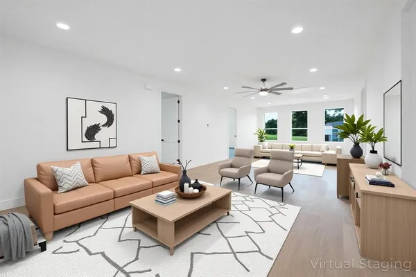 a living room with furniture kitchen view and a wooden floor