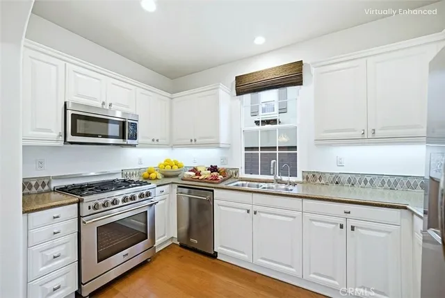 a kitchen with granite countertop white cabinets and stainless steel appliances