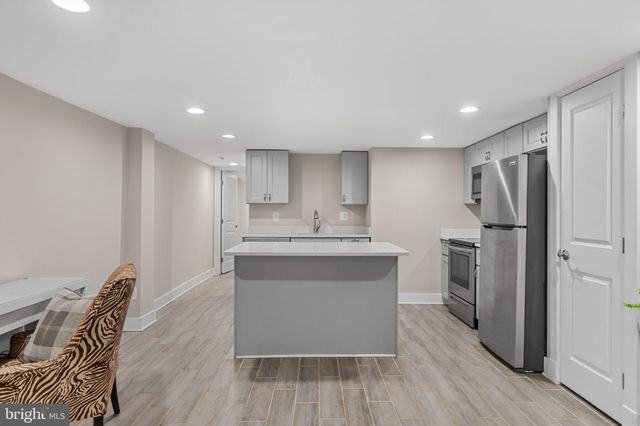 a spacious bedroom with a bed and a dresser with wooden floor