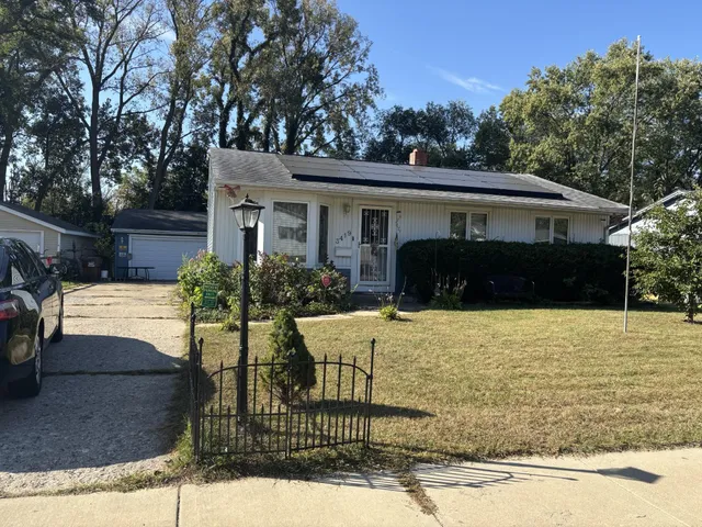 a front view of house with yard and trees in the background