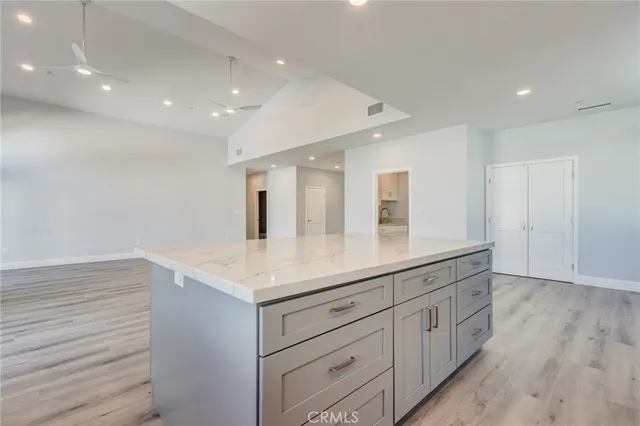 a kitchen with stainless steel appliances granite countertop a stove top oven a sink and white cabinets with wooden floor