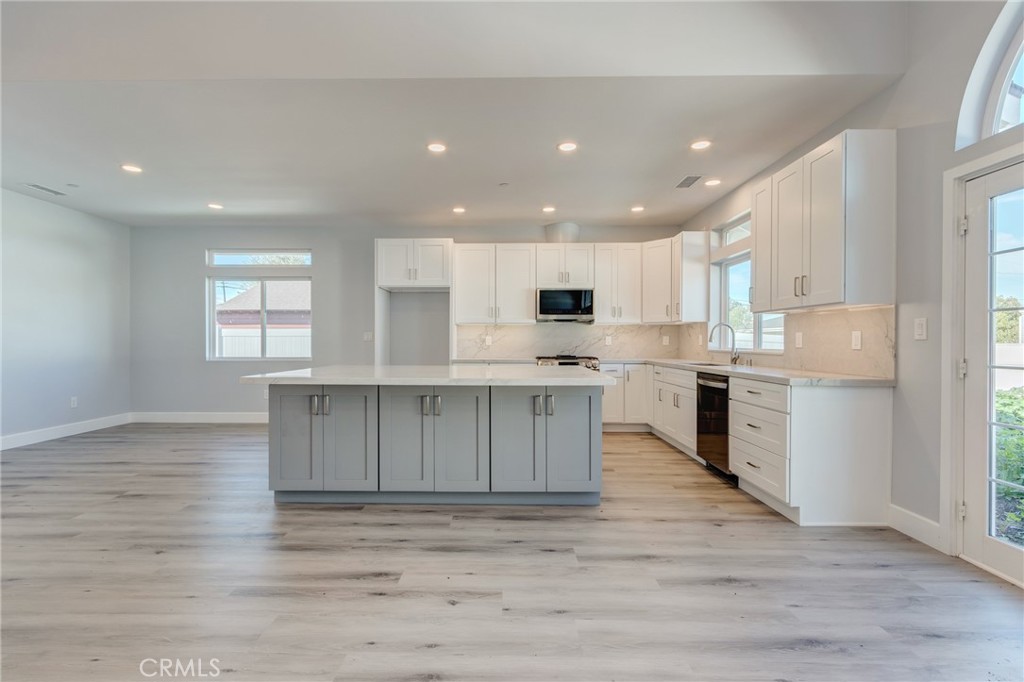 11128 Stamy Road Whittier, CA 90604 - Photo 20 of 40 a kitchen with stainless steel appliances granite countertop a stove top oven a sink and white cabinets with wooden floor