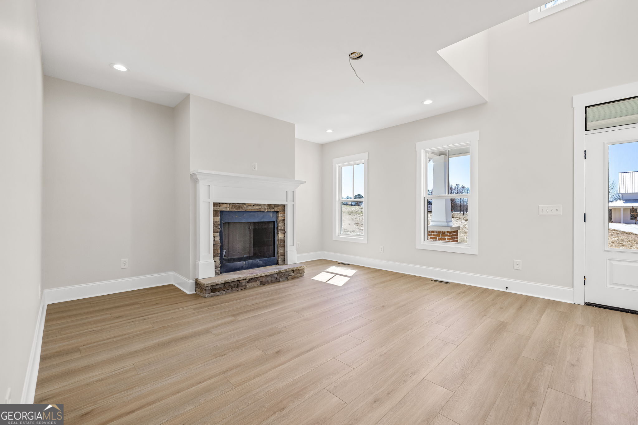 409 Roper Drive Clarkesville, GA 30523 - Photo 6 of 32 an empty room with wooden floor fireplace and windows