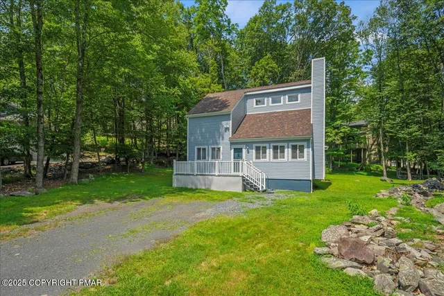 a front view of a house with garden and trees