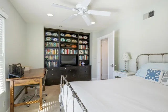 a bedroom with a bed a desk and book shelfs