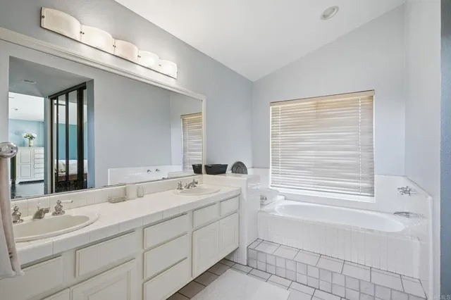 a spacious bathroom with double vanity a mirror and a bathtub