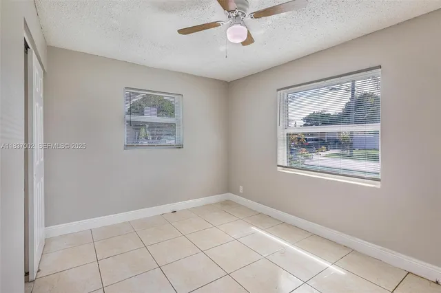 a view of an empty room with a window and a chandelier fan