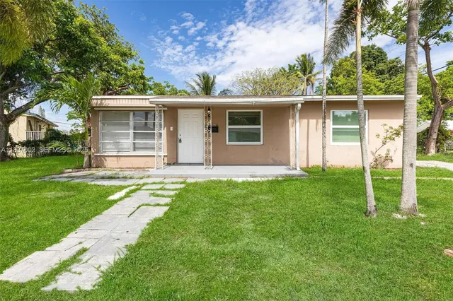 a backyard of a house with plants and large tree