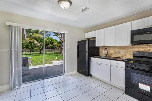 a kitchen with a refrigerator a stove top oven a sink and a window