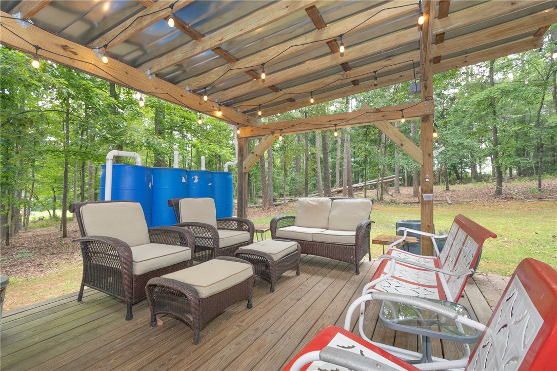 203 Oak Hollow Pendleton, SC 29670 - Photo 39 of 50 An inviting deck, shaded by a wooden and corrugated metal roof, offers a relaxed outdoor living space.