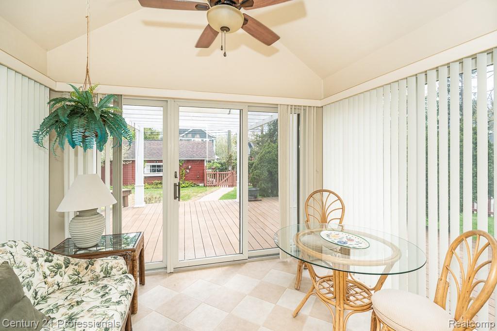 Sunroom featuring vaulted ceilings, a ceiling fan, and checkered tile flooring