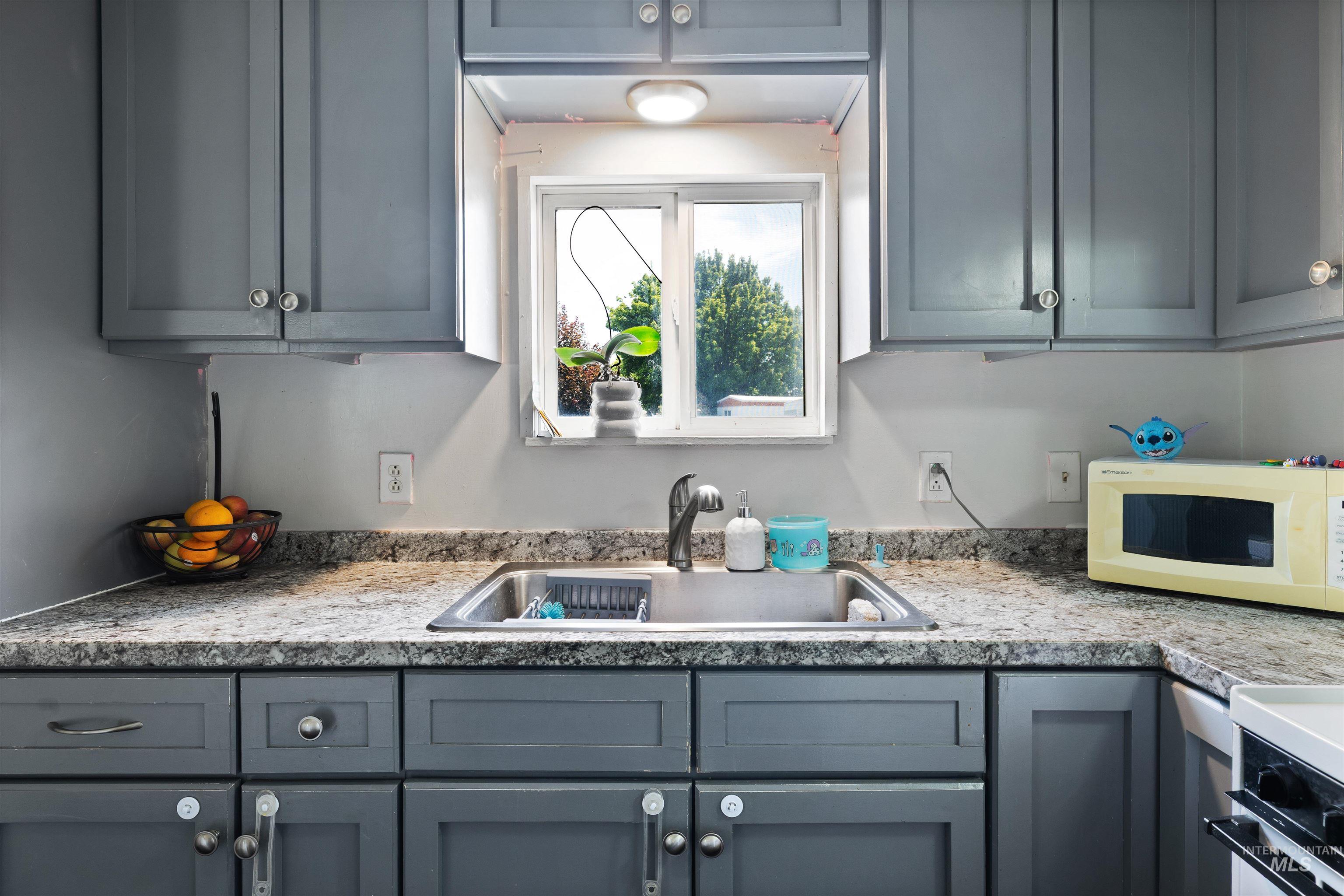 198 South Hills Road, Unit 65 Twin Falls, ID 83301 - Photo 5 of 16 Kitchen featuring gray cabinetry, a stainless steel sink, speckled countertops, and a window